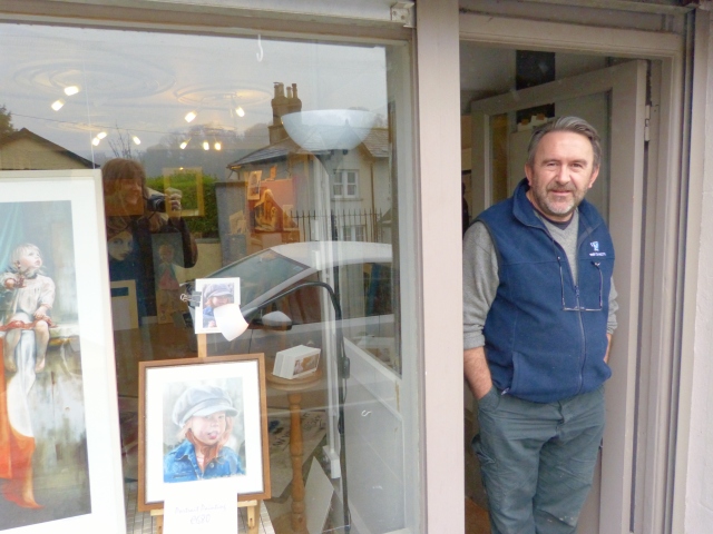 Neil outside his studio in Enniskerry, with a print of 'Upon Small Shoulders' in the window, beside a portrait of the tiny model's beautiful red-headed sister